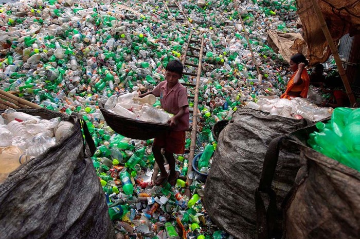 A Bangladeshi child laborer carries empty bottles at a plastic bottle recycling center in Dhaka, Bangladesh, Tuesday, Sept. 18, 2012. (AP Photo/A.M. Ahad)